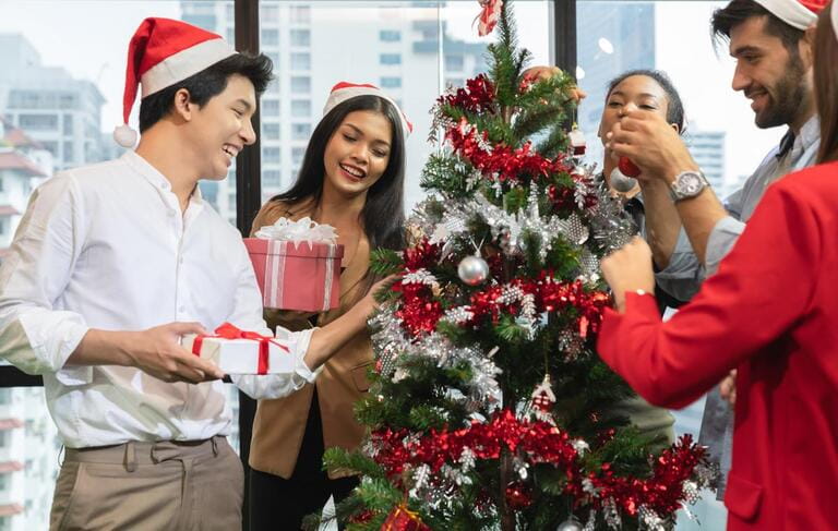 Group of diversity young creative happy celebrating Merry Christmas and Happy New Year decorating Christmas tree in office in modern office Group of diversity young creative happy celebrating Merry Christmas and Happy New Year decorating Christmas tree in office in modern office