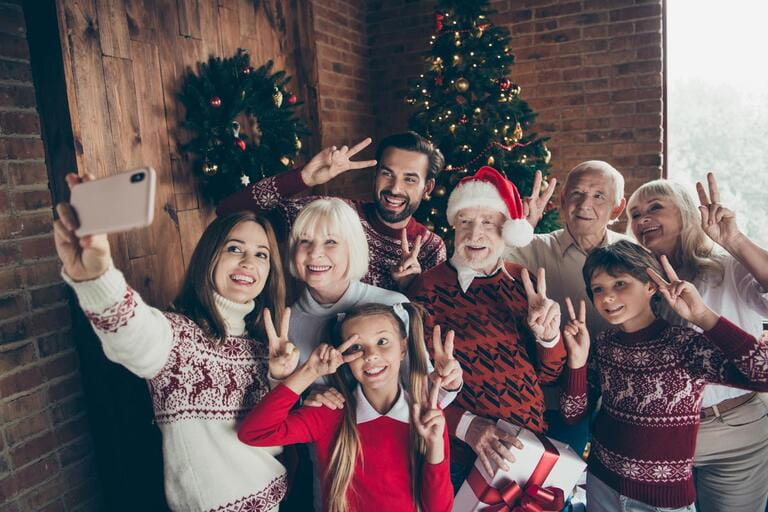 Fun full family showing two finger festure v-sign. Christmas gathering. Happy grandparents brother and daughter taking selfies on mobile phones Fun full family showing two finger festure v-sign. Christmas gathering. Happy grandparents brother and daughter taking selfies on mobile phones