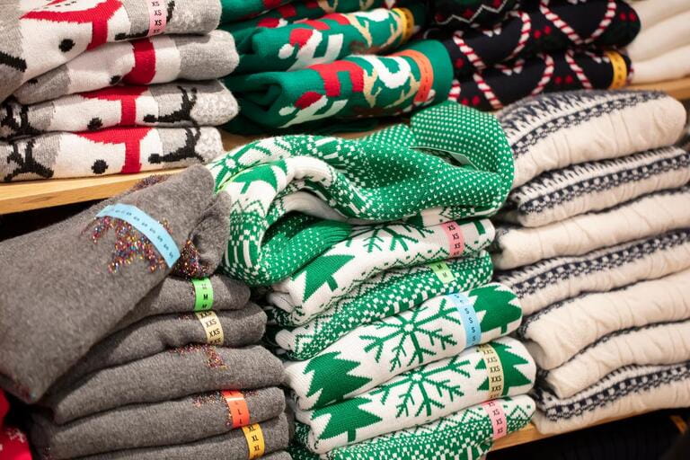 Sweaters with Christmas ornaments in the store.Stack of folded knitted