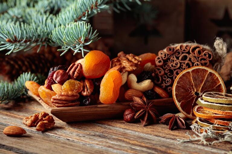 Dried fruits and nuts on an old wooden table. Christmas still-life with dried citrus, apricots, raisins, various nuts, cinnamon sticks, and anise.