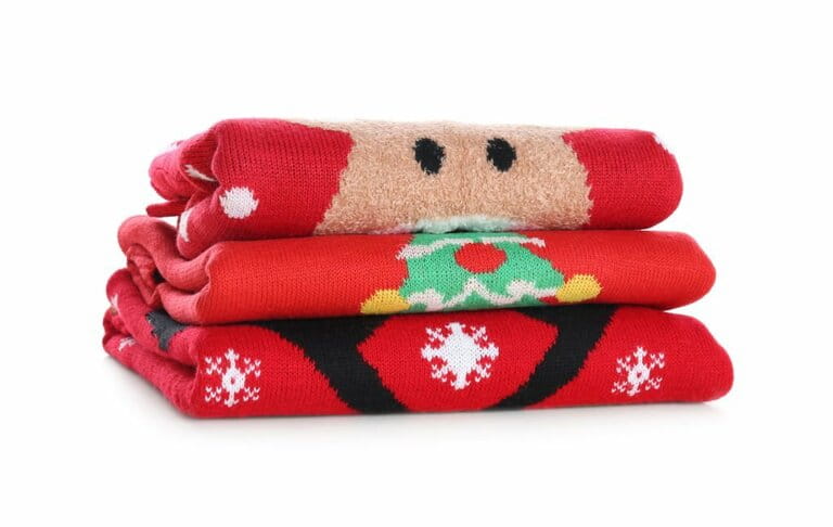 Stack of warm Christmas sweaters isolated on white