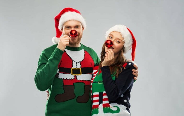 Happy couple in Christmas sweaters and Santa hats Happy couple in Christmas sweaters and Santa hats