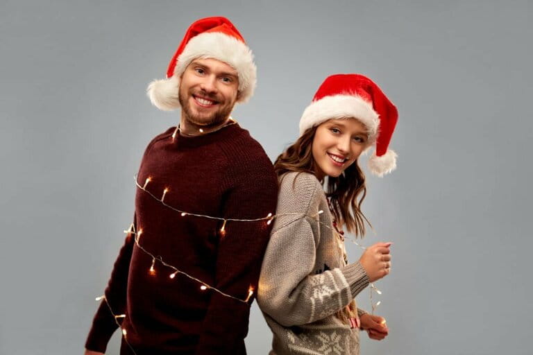 Happy couple in Christmas sweaters and Santa hats Happy couple in Christmas sweaters and Santa hats