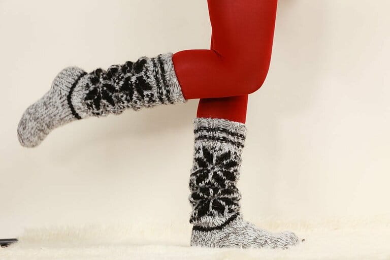 Women's legs wearing woolen socks and red tights Women's legs wearing woolen socks and red tights