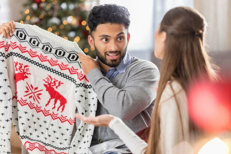 Man with funny expression holding up a Christmas sweater Man with funny expression holding up a Christmas sweater