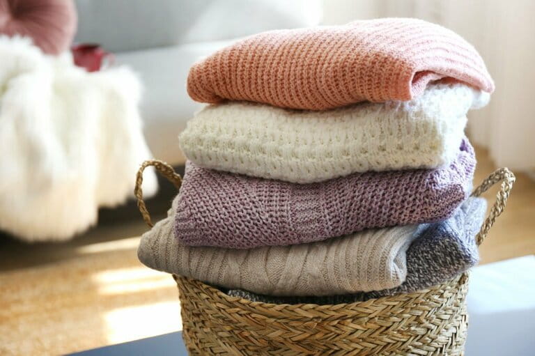 Piles of knitted sweaters of different colors and patterns are perfectly stacked on top of each other